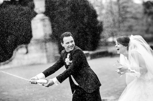 Romantische Hochzeitsfoto von Bräutigam öffnet Flasche Champagner