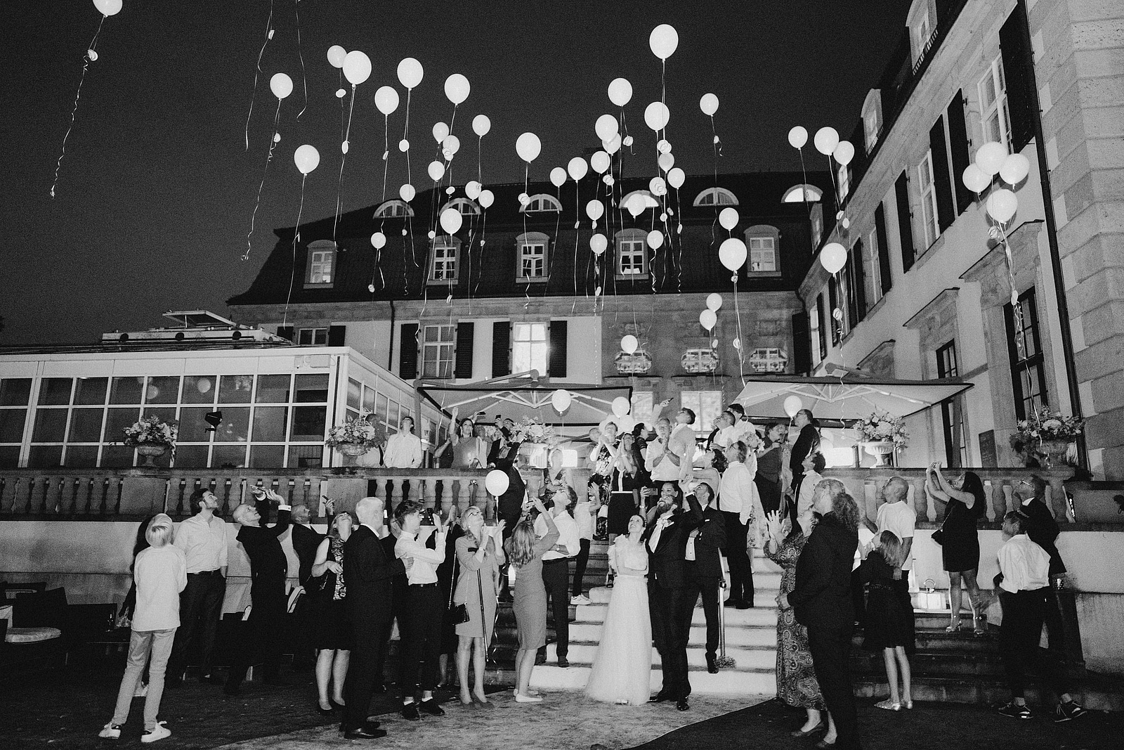 Das Brautpaar und seine Gäste lassen vor dem Schlosshotel Berlin weiße Luftballons in den Nachthimmel steigen.