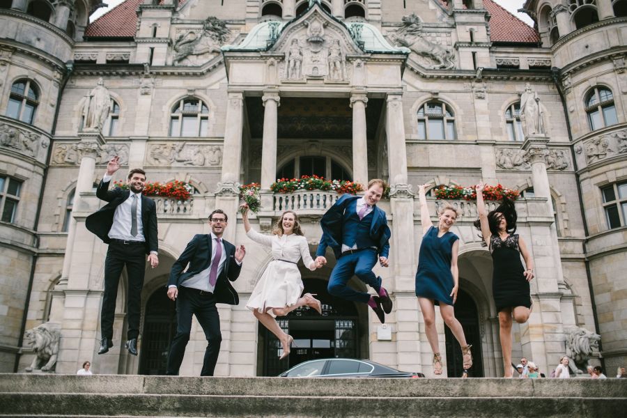 Brautpaar und Freunde springen vor dem Neuen Rathaus Hannover